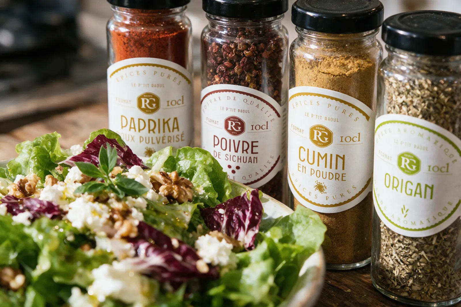 Pots d'épices Raoul Gey paprika, poivre, cumin et origan à côté d'une salade composée